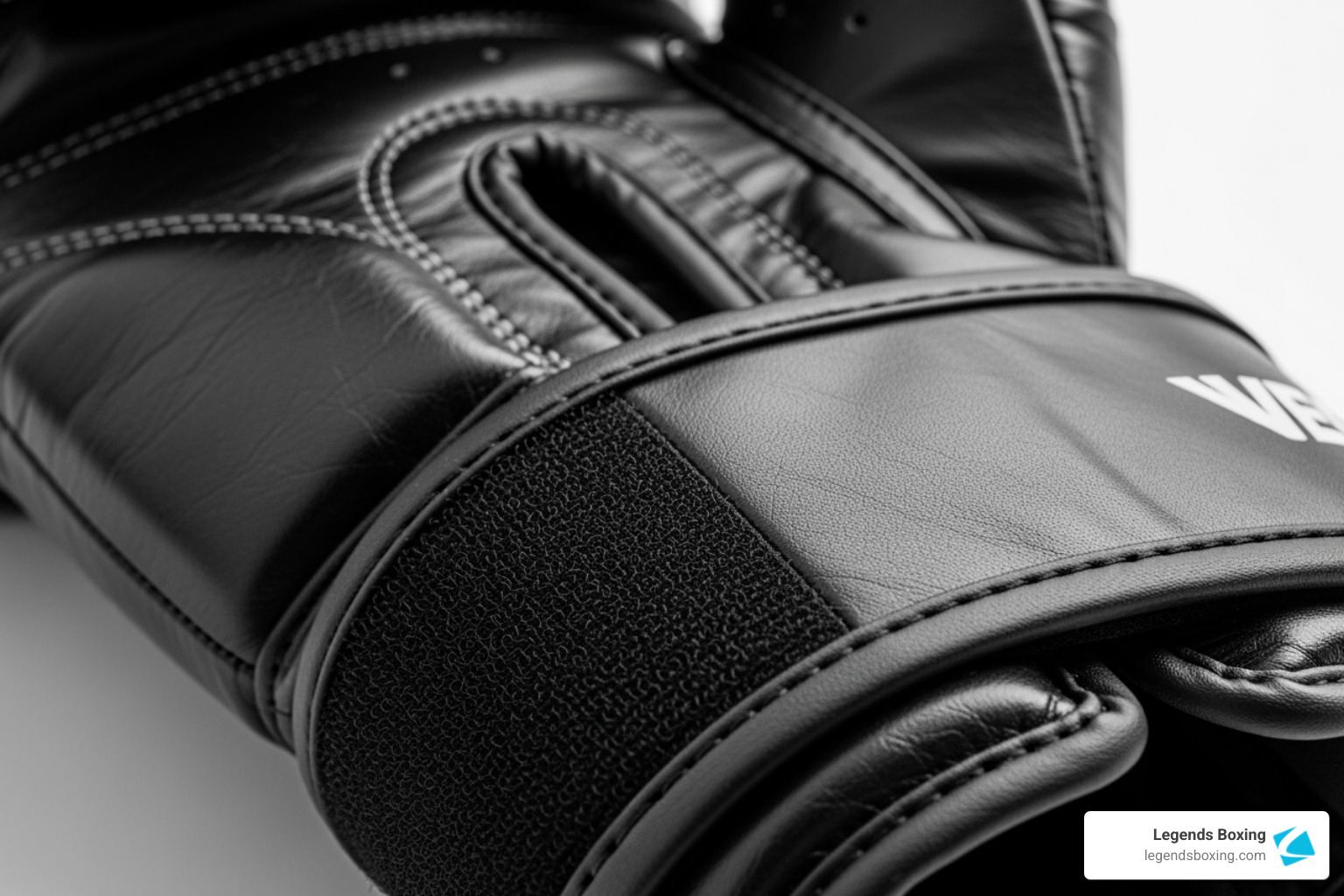 Extreme close-up of a black boxing glove Velcro wrist strap and leather construction — boxing glove closure system detail — Legends Boxing