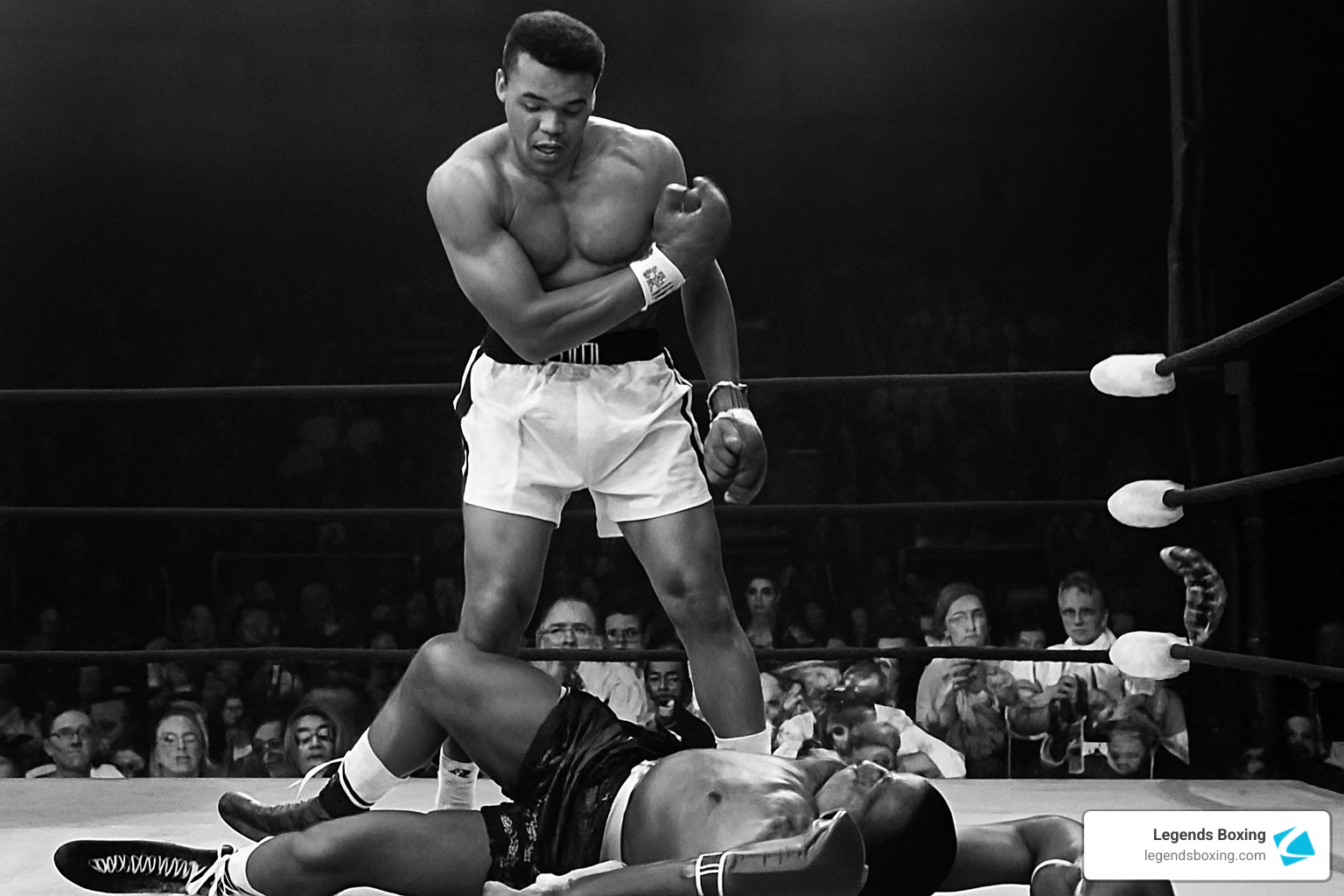 Classic black-and-white photograph of Muhammad Ali standing over Sonny Liston after a first-round knockdown, crowd and ringside photographers visible — one of the most iconic images in boxing history — Legends Boxing